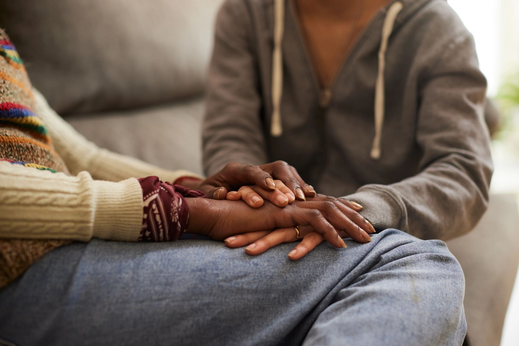 Two women holding hands in comfort and support